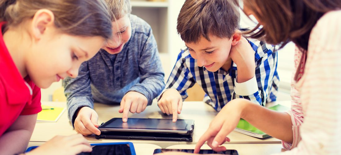 Grundschulkinder spielen mit Tablet-Computern